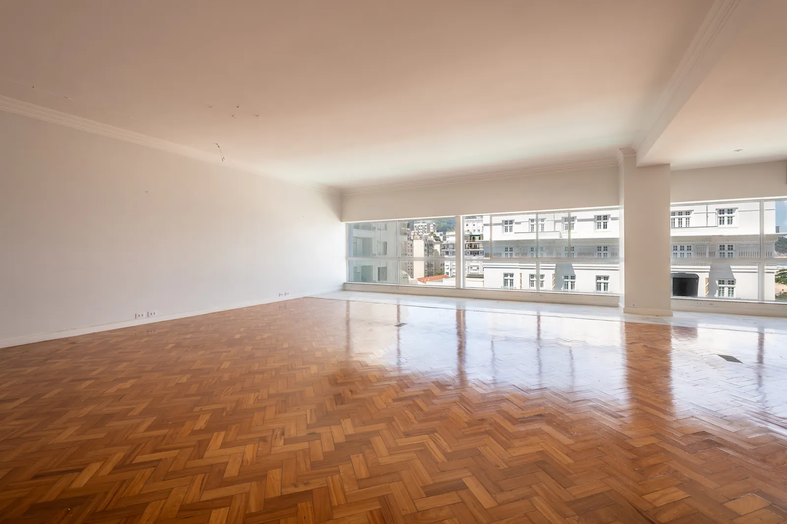 A bright reception room with panoramic windows and herringbone parquet
