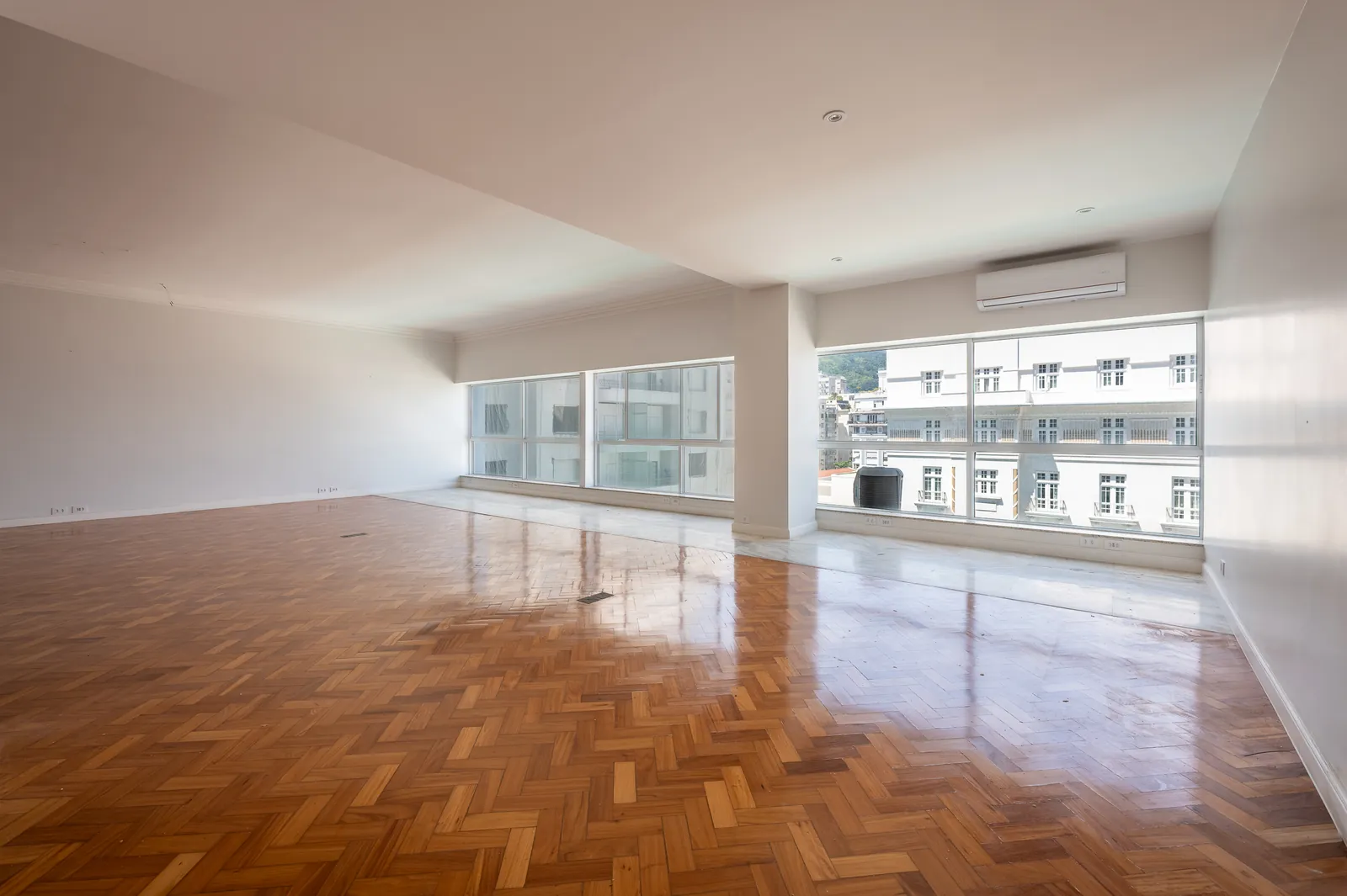 A large reception room with full-height glass and parquet